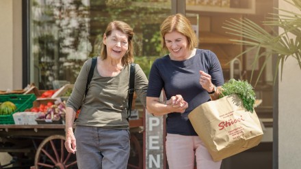 Freiwillige Duo-Partnerin unterstützt ältere Frau beim Einkaufen.