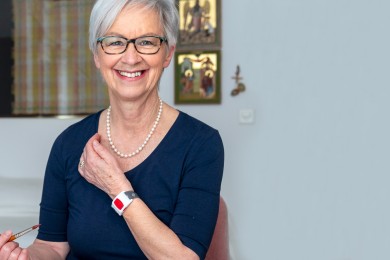 Eine Notrufkundin zeigt ihr Armband mit dem Notrufknopf.