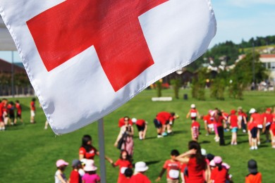 Freiwillige des Roten Kreuzes unter der Rotkreuz Fahne.