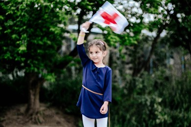 Kind hält die Fahne des Roten Kreuzes hoch an einem Anlass im Zoo Zürich.