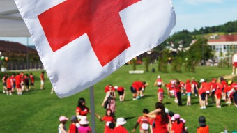 Freiwillige des Roten Kreuzes unter der Rotkreuz Fahne.