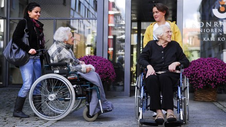 ältere Frauen im Rollstuhl vor dem Pflegeheim