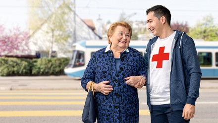 Ein Freiwilliger au dem ÖV-Begleitdienst unterstützt eine Seniorin, um Tram zu fahren