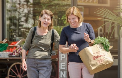 Freiwillige Duo-Partnerin unterstützt ältere Frau beim Einkaufen.