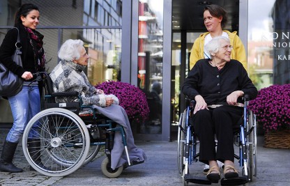 ältere Frauen im Rollstuhl vor dem Pflegeheim